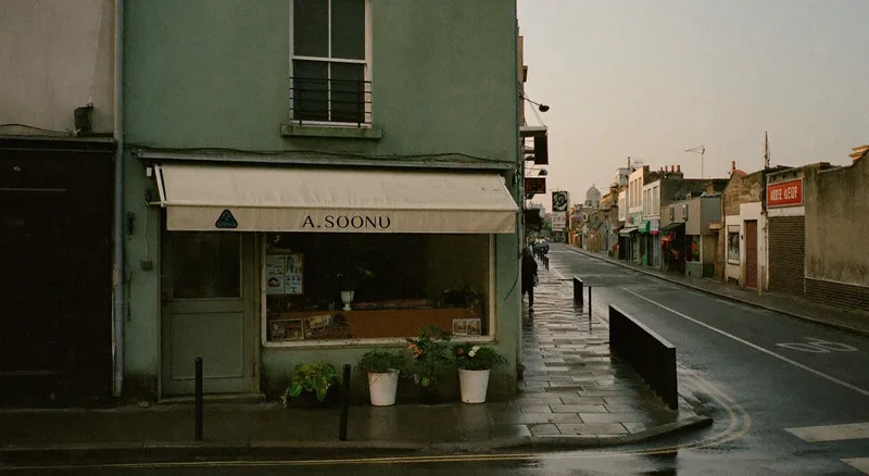 A small independent shopfront on a quiet high street in early morning light with a plain canvas awning